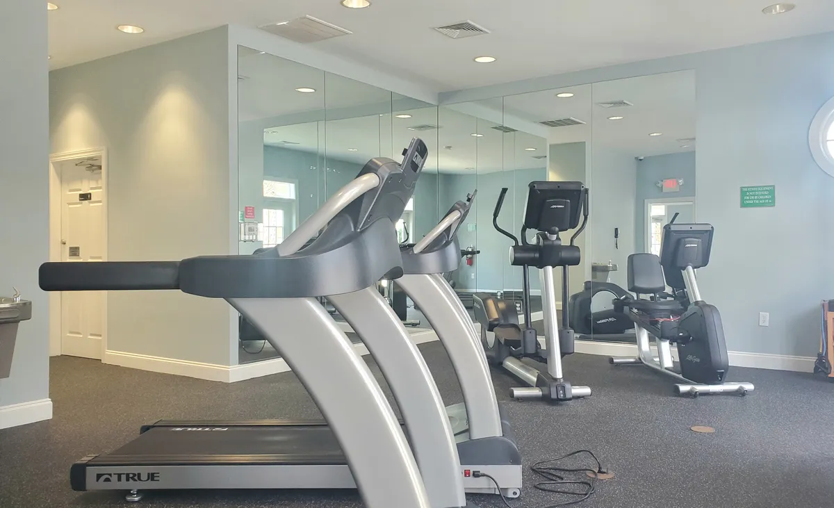 This image displays a well-equipped fitness center featuring modern cardio machines, including treadmills, ellipticals, and exercise bikes, with a mirrored wall reflecting the spaciousness of the area. The scene exudes an energetic and motivational atmosphere, ideal for guests looking to maintain their workout routine while traveling.