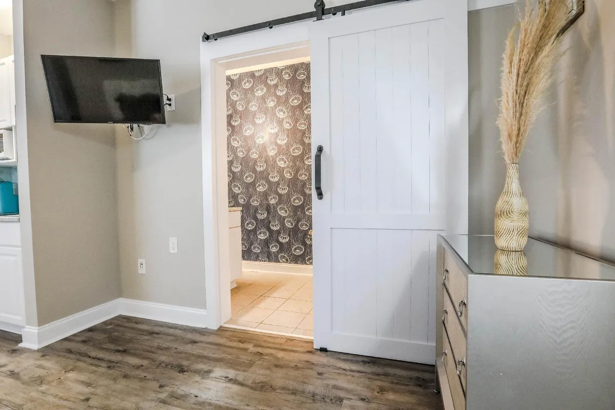 A modern living space featuring a stylish sliding barn door, a decorative vase, and a television. The room invites relaxation or entertainment, offering a cozy atmosphere for downtime between exploring the city or returning from a shift.